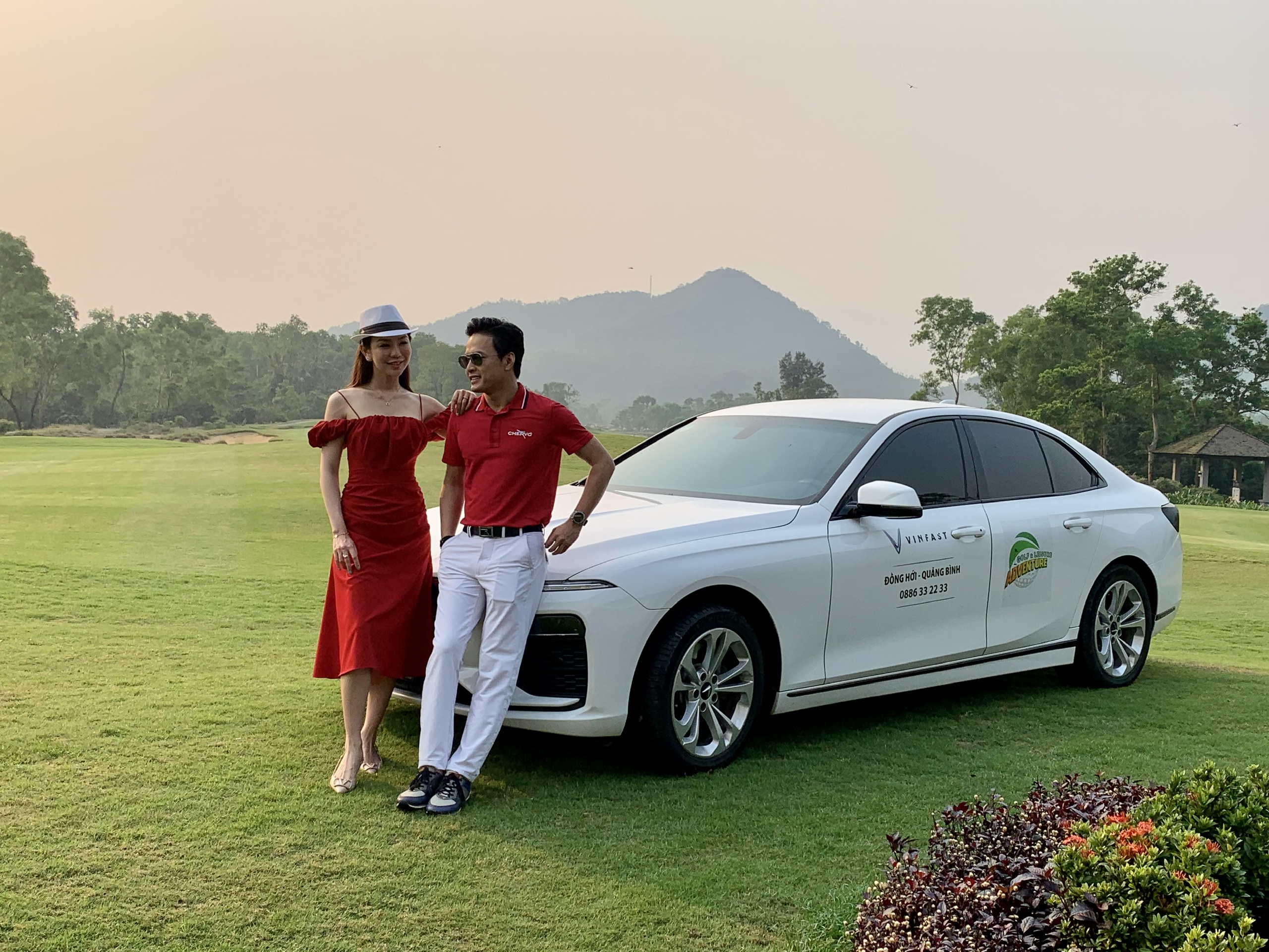 Diễn viên Hồng Đăng cùng Á hoàng Golf Queen trong sắc đỏ bên xe Vinfast tại sân golf Laguna Lăng Cô