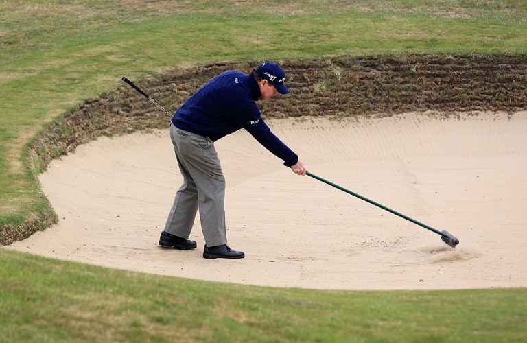 Golfer cào lại vết chân trong bunker 